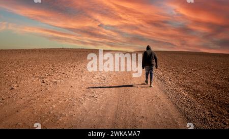 Un uomo che cammina sulla strada è circondato dal deserto Foto Stock