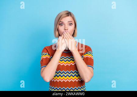 Foto di una donna spaventata senza parole con t-shirt in maglieria con parrucchiere con maniche coprire la bocca fissando isolata su sfondo di colore blu Foto Stock