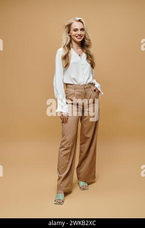 giovane donna alla moda in blusa bianca e pantaloni beige, un classico senza tempo Foto Stock