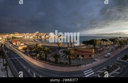Vue panoramique de la plage et du Village au lever du soleil sous un ciel orageux Foto Stock