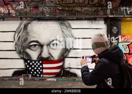 Londra, Regno Unito. 19 febbraio 2024. Un uomo fa una foto di un graffito raffigurante Julian Assange, con il suo cellulare. Un graffito è visibile a Leake Street, il famoso tunnel di graffiti nel centro di Londra, dipinto dall'artista di strada Dave Paint, raffigurante Julian Assange, l'OMS è in attesa dell'udienza finale alla Royal Court of Justice di Londra del 20 febbraio 2024 sulla decisione di essere estradata negli Stati Uniti per l'accusa di aver esposto la politica diplomatica e militare nelle guerre afghane e in Iraq attraverso WikiLeaks. Credito: SOPA Images Limited/Alamy Live News Foto Stock