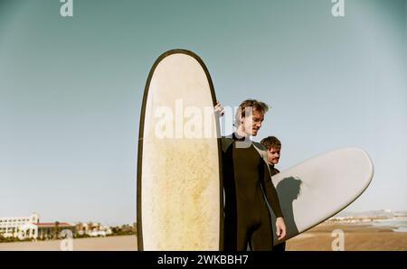 Gruppo di amici surfisti in muta con tavole da surf e si preparano a cavalcare sulle onde Foto Stock