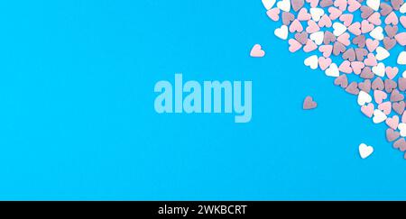San Valentino. Cuori multicolore sono disposti nell'angolo. Cuori rosa e bianchi su sfondo blu. Tanti piccoli cuori. Copia spazio per il testo Foto Stock