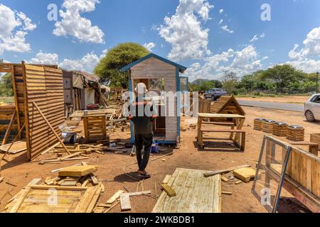 lavoratore di falegname afroamericano sul suo posto di lavoro che fa le case wendy sul lato della strada Foto Stock