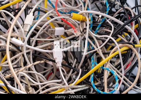 Una pila di cavi, connettori e spine per periferiche tecnologiche utilizzate, inclusi standard universali per computer, cavi audio e video, e-waste con Foto Stock