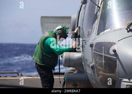 240215-N-CD319-1054 PHILIPPINE SEA (15 febbraio 2024) Aviation Electrician's Mate 3rd Class Sergio Rocha, da Austin, Texas, esegue un controllo dell'equipaggiamento pre-volo su un elicottero MH-60R Sea Hawk, assegnato ai "Blue Hawks" dell'Helicopter Maritime Strike Squadron (HSM) 78, a bordo del cacciatorpediniere missilistico guidato classe Arleigh Burke USS William P. Lawrence (DDG 110). Lawrence è assegnato al Carrier Strike Group ONE e schierato nella 7th Fleet area of Operations a supporto di un Indo-Pacifico libero e aperto. (Foto della Marina degli Stati Uniti di Tristan Cookson, specialista della comunicazione di massa di seconda classe) Foto Stock