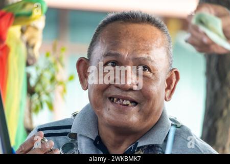 AYUTTHAYA, THAILANDIA, DEC 10 2023, Ritratto di un uomo anziano allegro che esamina gioielli per strada Foto Stock