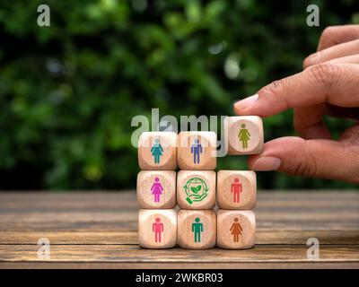 Membri della comunità della società Green Life, ecosostenibilità cooperativa, concetti di responsabilità ambientale. Icona umana in mano messa su un blocco di cubi di legno Foto Stock