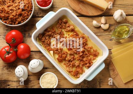 Cottura delle lasagne. Fogli di pasta, carne macinata nel vassoio da forno e prodotti su tavolo di legno, piatti Foto Stock