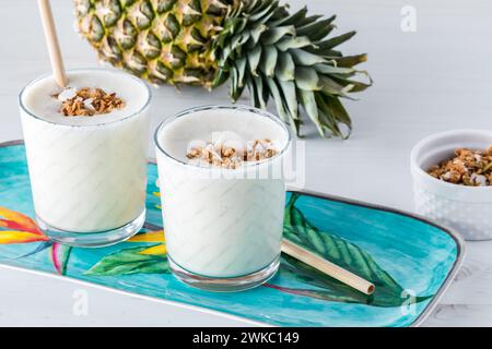 Frullati rinfrescanti di ananas e cocco su un vassoio, pronti per essere bevuti. Foto Stock