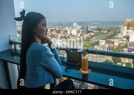 Profilo di una bella giovane donna cambogiana che ammira la vista aerea da uno skybar/fiume Mekong sullo sfondo. Phnom Penh, Cambogia. © Kraig Lieb Foto Stock