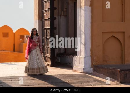 Jaipur, India 16 febbraio 2024 sposa indiana in posa per un servizio fotografico in abito da sposa tradizionale rosso e oro a Amer Fort Foto Stock