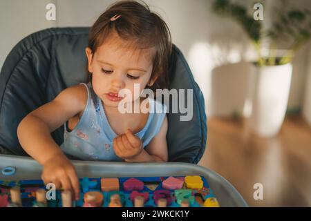 Ragazzina che gioca con numeri, forme e lettere ecologiche in legno sul tavolo. Gioco intellettuale. Sviluppo precoce. Foto Stock