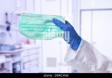 Mano del medico maschio che tiene una maschera verde all'ospedale Foto Stock