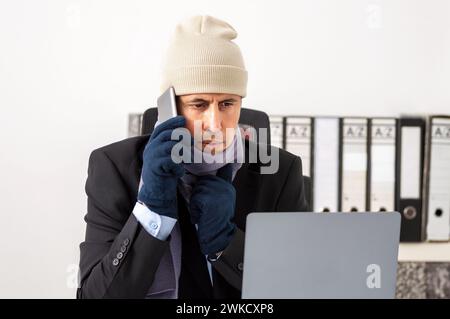 Dirigente preoccupato che è freddo e chiama il servizio tecnico per la riparazione del riscaldamento in ufficio Foto Stock