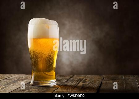 bicchiere di birra bionda con schiuma su sfondo scuro. Foto Stock