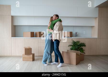 Un uomo amorevole che abbraccia una donna amata sposta un nuovo appartamento da sogno. Abbracciate la coppia di famiglie nel giorno del trasferimento. Foto Stock