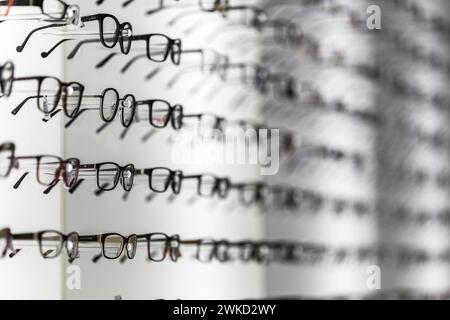 Occhiali da sole eleganti e moderni e molti altri occhiali da vista in fila esposti in un negozio Foto Stock