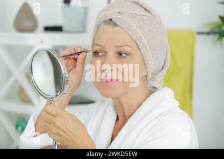 Donna spiumatura sopracciglia mediante la finestra Foto Stock