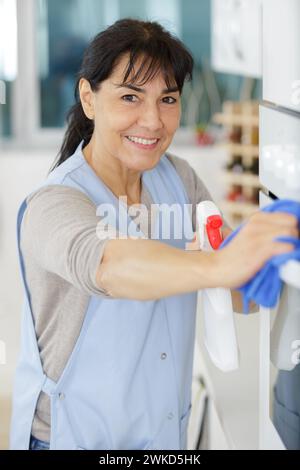 donna blu che pulisce la polvere dal muro e pulisce la casa Foto Stock