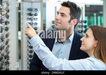 coppia sorridente che sceglie le cornici per occhiali da sole nel negozio di ottica Foto Stock