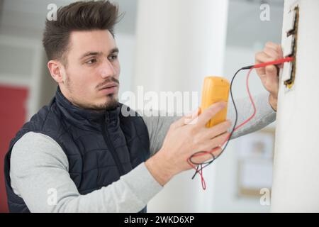 l'elettricista utilizza un misuratore digitale per misurare la tensione Foto Stock