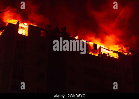 Un enorme incendio scoppia in un edificio di appartamenti a più piani. La casa in fiamme è inghiottita di notte durante il disastroso Foto Stock