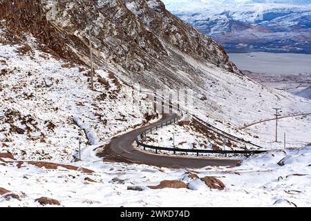 Applecross peninsulare Scotland Bealach na Bà guardando indietro lungo la tortuosa e ripida strada verso le montagne innevate e Loch in inverno Foto Stock