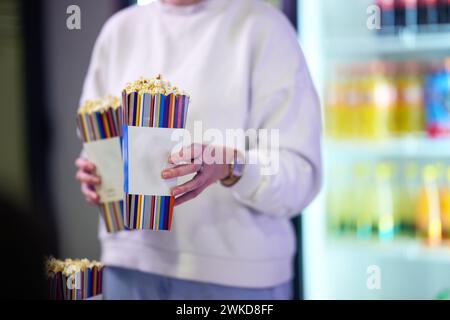 Un venditore si trova fuori dal cinema, tenendo popcorn appena fatti da vendere ai cineasti prima che entrino nel teatro Foto Stock