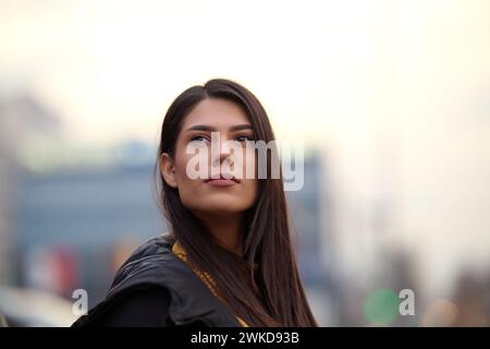 Una bella donna posa per un ritratto in un ambiente urbano, trasuda fiducia ed eleganza nel vivace ambiente cittadino Foto Stock