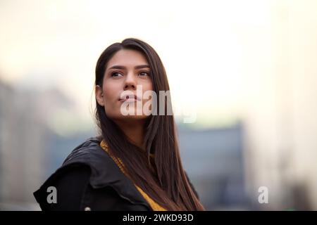 Una bella donna posa per un ritratto in un ambiente urbano, trasuda fiducia ed eleganza nel vivace ambiente cittadino Foto Stock