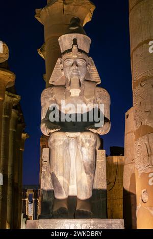 Statua colossale di Ramses II (Ramses II) nel tempio di Luxor illuminata di notte, a Luxor, Egitto Foto Stock