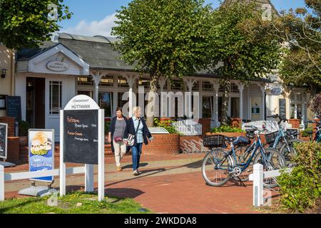 Straßenszenen aus Norddorf auf der Nordseeinsel Amrum im Sommer Hotel Hüttmann zwei Frauen verlassen das Gebäude *** Scene di strada da Norddorf sull'isola di Amrum nel Mare del Nord in estate Hotel Hüttmann due donne che lasciano l'edificio Foto Stock