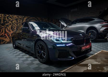 La berlina nera BMW si trova in un garage di lusso, decorato con arredi artistici. Foto Stock