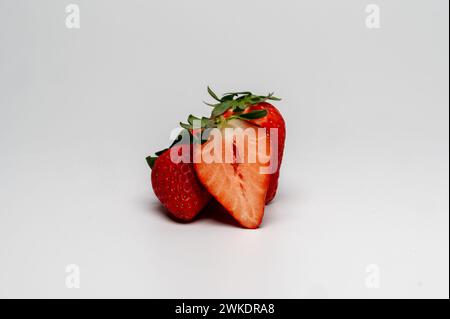 , Food, Deutschland, 20.02.2024, Drei reife Erdbeeren, eine aufgeschnitten, auf weißem Hintergrund. Foto Stock