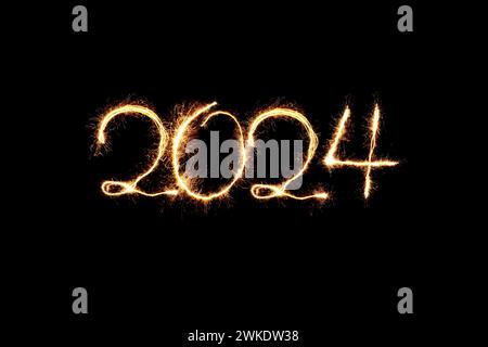 Capodanno 2024 sparkler luce dorata. Gli scintillanti disegnano le figure 2024. Luci e lettere del Bengala. Tessera festività 2024. Foto Stock