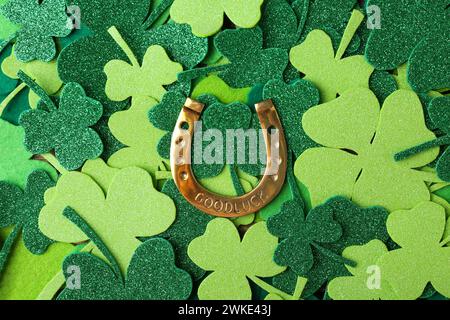 St Il giorno di Patrick. Ferro di cavallo dorato su foglie di trifoglio decorativo verde, vista dall'alto Foto Stock