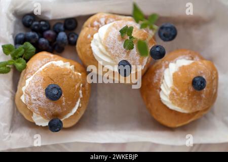Vista dall'alto di tre torte Semla su una scatola di legno con frutti di bosco. vista dall'alto della semla Foto Stock