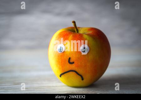 Augusta, Baviera, Germania - 18 febbraio 2024: Concetto di salute mentale e dolore, una mela dal volto triste *** Mentale Gesundheit und Trauer Konzept, ein Apfel mit einem traurigen Gesicht alleine Foto Stock