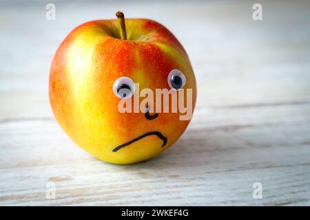 Augusta, Baviera, Germania - 18 febbraio 2024: Concetto di salute mentale e dolore, una mela dal volto triste *** Mentale Gesundheit und Trauer Konzept, ein Apfel mit einem traurigen Gesicht alleine Foto Stock