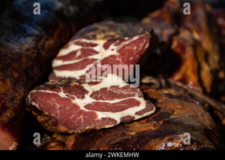 Deliziosi pezzi di carne affumicata esposti per la vendita nel mercato presentato per la vendita in un mercato agricolo nel villaggio di Kacarevo, pancetta gastro e carne secca Foto Stock