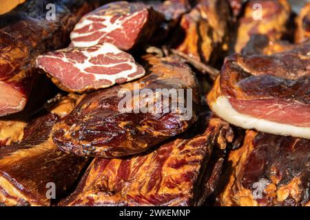 Deliziosi pezzi di carne affumicata esposti per la vendita nel mercato presentato per la vendita in un mercato agricolo nel villaggio di Kacarevo, pancetta gastro e carne secca Foto Stock