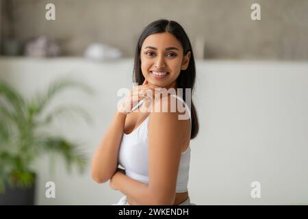Felice donna indiana in bianco top che posa in bagno Foto Stock