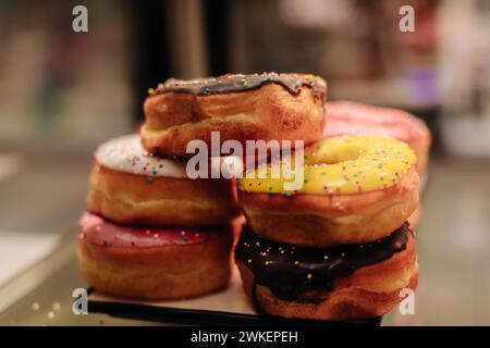 Ciambelle dolci colorate appena sfornate con condimento cremoso Foto Stock