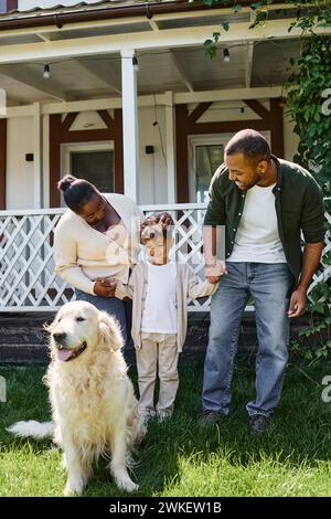 momenti felici, genitori afroamericani e figlio sorridenti vicino al cane di famiglia sul cortile di casa Foto Stock