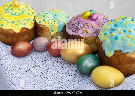 Diverse torte pasquali al forno e uova colorate su una tovaglia di pizzo Foto Stock