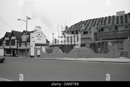 1987, un nuovo edificio in mattoni costruito accanto ad una taverna in legno del XV secolo, The Black Swan Inn, Peasholme Green, Helmsley, York, Inghilterra, REGNO UNITO. La vecchia locanda o taverna fu costruita originariamente come casa per la famiglia Bowes. Il nuovo edificio in mattoni accanto ad esso, He Peasholme Centre, fu costruito come ostello per i senzatetto locali. Questo edificio moderno aveva una vita molto più breve, essendo stato demolito nel 2010. Foto Stock