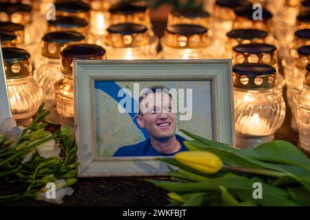 Fiori e candele posate al memoriale spontaneo per il leader dell'opposizione russa Alexei Navalny, con un ritratto sorridente bagnato dalla neve e dalle gocce di pioggia Foto Stock