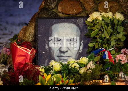 Fiori e candele posate al memoriale spontaneo per il leader dell'opposizione russa Alexei Navalny, con un ritratto in bianco e nero bagnato dalla neve Foto Stock