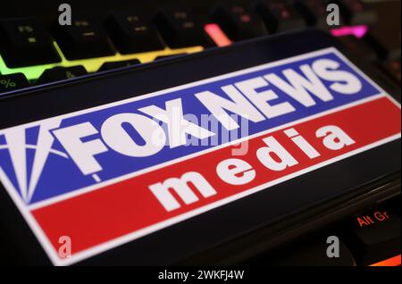 Viersen, Germania - 9 gennaio. 2024: Primo piano del telefono cellulare con il canale Fox news sulla tastiera del computer Foto Stock